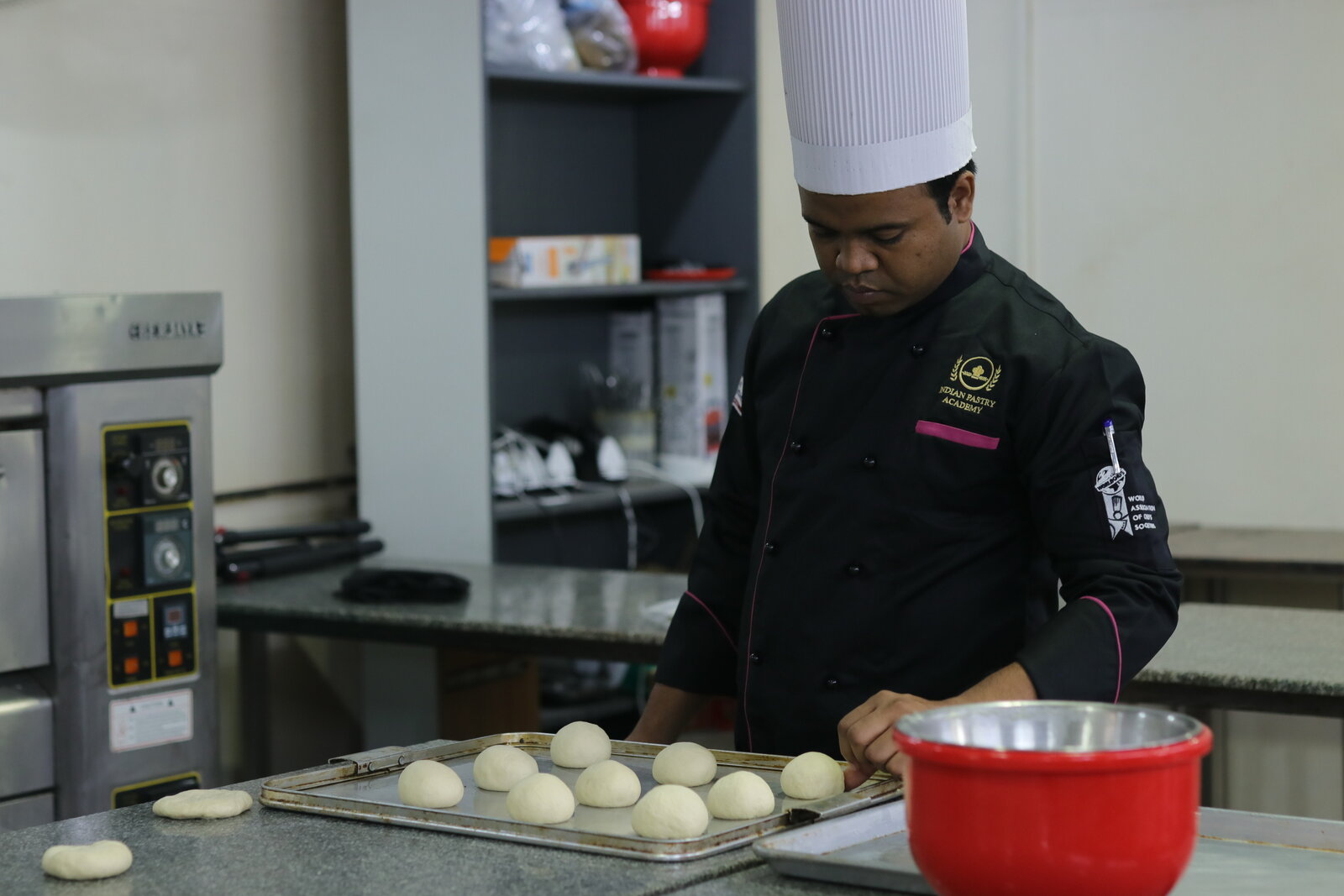 Indian Pastry Academy student shaping portioned dough balls for proofing