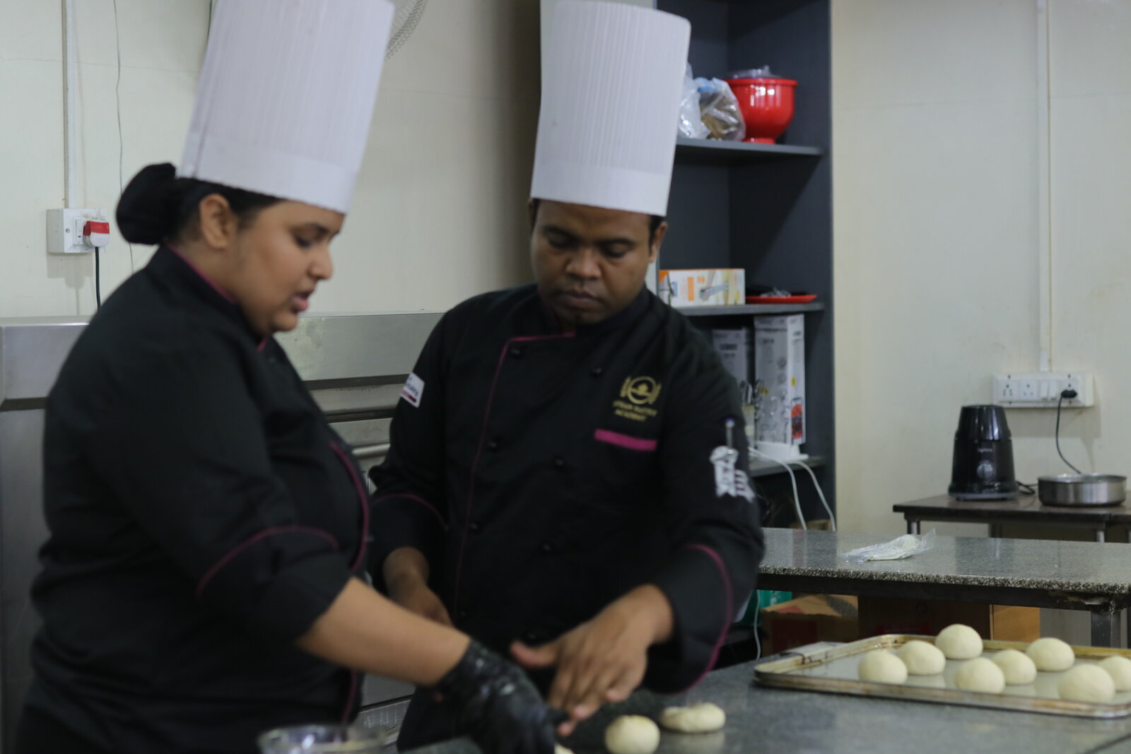 Indian Pastry Academy students shaping and portioning dough together during a studio session