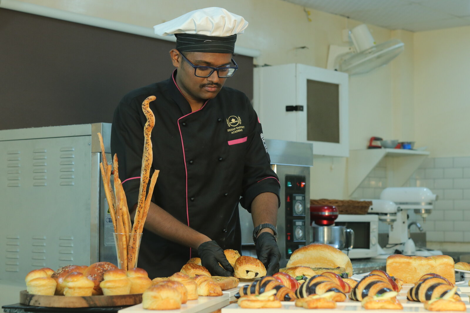 Student arranging a viennoiserie and bread display at Indian Pastry Academy in Bangalore